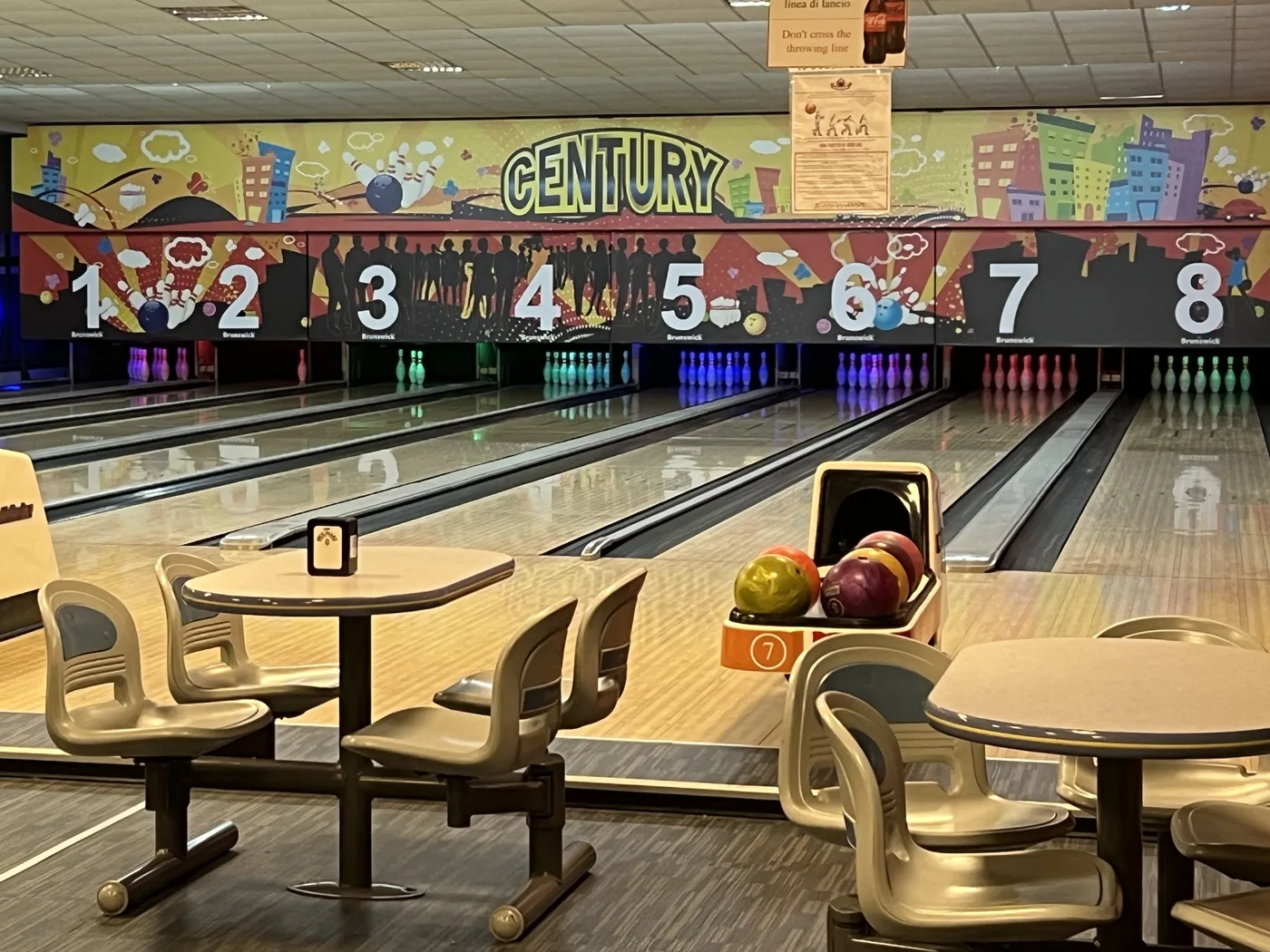 Le piste da bowling del Century, con il murale e i tavolini davanti